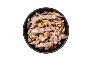 Slow shredded puilled pork meat in a pan with butcher knife. Isolated on white background. photo