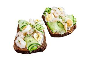 Sandwiches with shrimp, prawns, quail eggs and cucumber on rye bread. Isolated on white background, Top view. photo