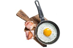 Fried egg in a frying pan with tomatoes and bacon. Isolated, white background. photo