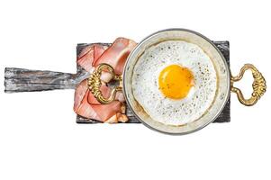 Breakfast with fried egg in a skilet with tomatoes and bacon. Isolated, white background. photo