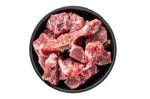Raw diced meat cubes with bone in a pan. Isolated on white background. photo