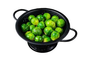 Brussels sprouts green cabbage in colander. Isolated on white background, top view. photo