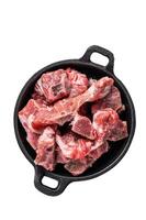Raw diced meat cubes with bone in a pan. Isolated, white background. photo