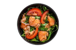 Fresh salmon salad with arugula, tomato and green vegetables. Isolated on white background. photo