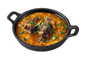 Kharcho soup with beef meat, rice, tomatoes and spices in a pan. Isolated on white background, top view. photo
