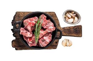 Raw diced meat cubes with bone in a pan. Isolated, white background. photo
