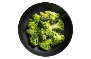 Boiled broccoli with spices in a plate. Isolated, white background. Top view. photo