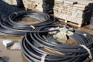 The construction site currently in progress features coiled black pipes along with stone pavers prominently visible photo