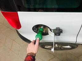 A person is currently engaged in the important action of pumping gas into a whitecolored automobile, ensuring that it is properly refueled and ready for its next journey or travel plans photo