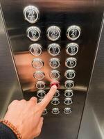 An elevator button panel featuring a hand actively pressing the button for the desired selected floor, showcasing modern technology and convenience photo