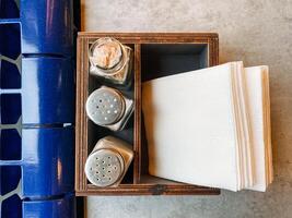 A beautifully designed wooden box elegantly holding salt and pepper shakers, with neatly folded napkins inside, showcasing a rustic yet stylish dining accessory for meal settings photo