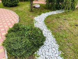 A picturesque path in a beautifully maintained garden, featuring white decorative rocks along with a charming brick walkway that invites visitors to enjoy the surrounding beauty of nature photo