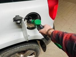 A person is actively engaged in the process of pumping gasoline into a cars fuel tank, ensuring that the tank is adequately filled for the journey that lies ahead of them photo