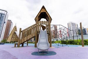 A contemporary playground structure complete with a slide and various climbing features beautifully situated amidst urban architecture photo