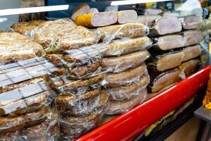 A display case that is filled with a wide variety of meats all in plastic wrap photo