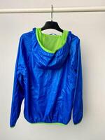 A stylish blue jacket that features a green hood is hanging on a rack photo