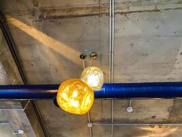 There is a ceiling that features a blue pipe prominently alongside it, with two stylish lights elegantly hanging down from it, contributing to the overall ambiance of the room photo
