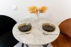 A beautifully set dining table adorned with elegant plates, fine utensils, and a stylish vase filled with fresh flowers, creating an enticing and charming ambiance for any meal occasion photo