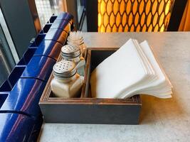 Condiment Holder with Salt and Pepper Shakers and Napkins on Caf Table photo