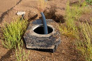 A pipe is protruding from a hole that has been dug into the ground, creating an unusual sight. This scenario encompasses various elements like plants, grass, and natural landscape features photo