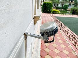 A security camera has been carefully mounted to the side of a building, ensuring that the area is monitored for any unusual activity while also enhancing safety in the surroundings photo