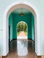 An elegantly designed archway connects a stunning hallway to a serene park, creating a seamless transition that enhances the overall ambiance and experience of the space photo