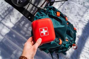 Person with electric blue helmet making a gesture in front of a backpack photo