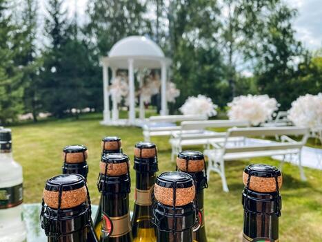 A diverse collection of wine bottles is neatly arranged on a table in front of a beautifully crafted gazebo, creating an inviting and tranquil atmosphere for visitors and attendees photo
