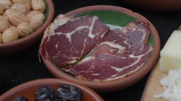 Deliciously Sliced Cured Meat Presented on a Rustic Plate, Accompanied by Tasty Extras video