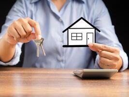 A businessman's hands holding keys and a mini paper house while sitting in the office photo