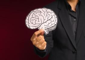 Close-up of hand holding a brain shape made from paper standing on a red background photo