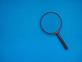 Search concept. A magnifying glass on a blue background with copy space for text photo