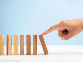 Risk and strategy in business concept. Close-up of hand push a wooden block on a line of domino photo