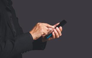 Close-up of hands businessman in a suit using a mobile phone while standing over a gray background photo