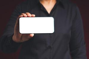Hand holding a blank screen smartphone while standing on a black background photo