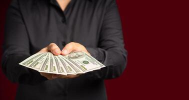 Businessman holding US banknotes on a red background while standing in the studio photo