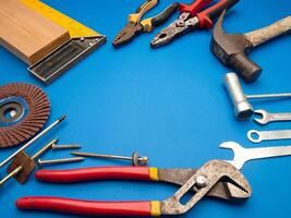Work tools on a blue background. A hammer, screwdriver, spanner, and pliers photo