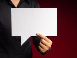 Hand holding a white speech bubble against a red background while standing in the studio photo