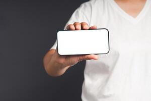 Hand holding a blank screen smartphone while standing on a gray background photo