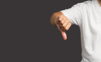 Close-up of man hand showing thumbs down while standing on a gray background. photo