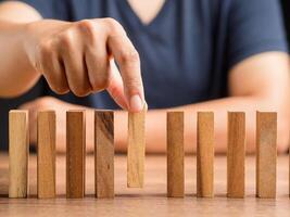 Man in casual picking one wooden block from many wooden blocks in a row on the desk photo