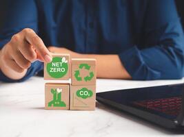 Hand holding a wooden cube with green icons over a marble table while sitting in the office photo