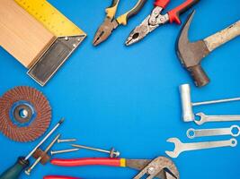 Work tools on a blue background. A hammer, screwdriver, spanner, and pliers photo