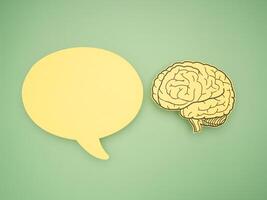 Yellow speech bubble and a brain shape made from paper on a green background photo