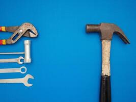 Work tools on a blue background. A hammer, screwdriver, spanner, and pliers photo