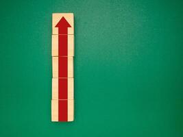Wooden cubes with red arrows up over a green background. Business growth and strategy concept photo