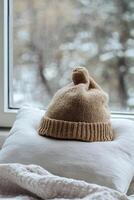 Cozy Winter Scene with Knitted Hat on Pillow by Window Overlooking Snowy Landscape photo