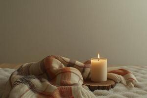 A candle is lit on a wooden table next to a blanket photo