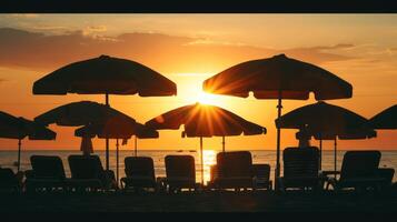 Bold silhouette of beach umbrellas and chairs against the setting sun photo