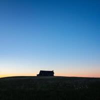 A house is on a hill in a field photo